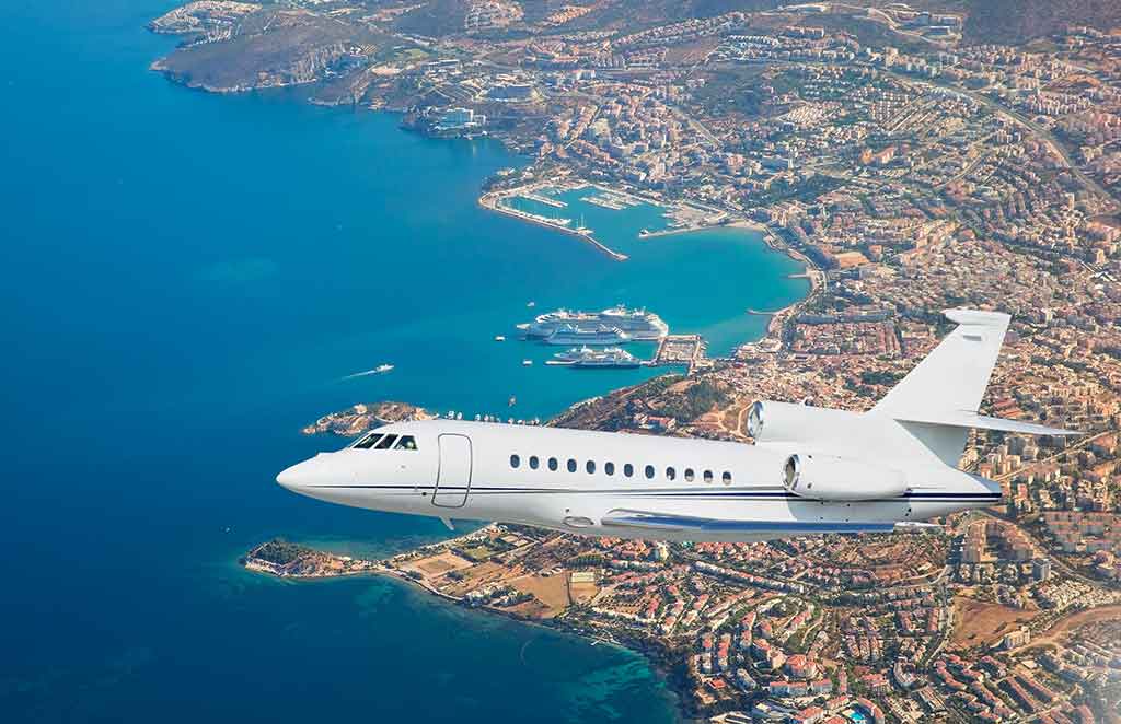 A private jet flys above a luxury destination