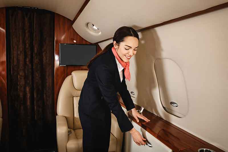 A private jet flight attendant performs tasks before takeoff. 