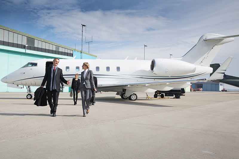 Business executives depart a private jet.