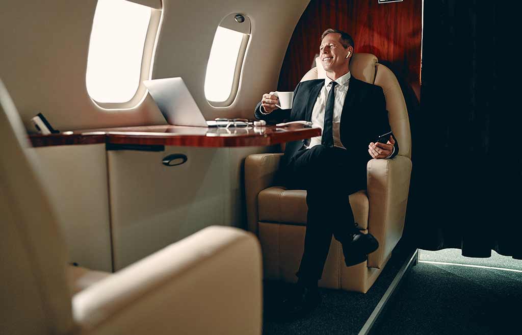 Businessman flies private while staring out the window and drinking a cup of espresso